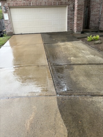 Professional surface-cleaning equipment mid-process on a residential concrete driveway in Katy, TX, showing the cleaned and untreated sections side by side